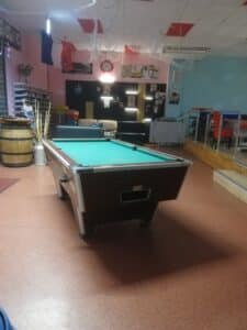 Salle de loisirs ambiance rétro avec table de billard, canapés, mur Marilyn Monroe, drapeaux français et chaussures de bowling.